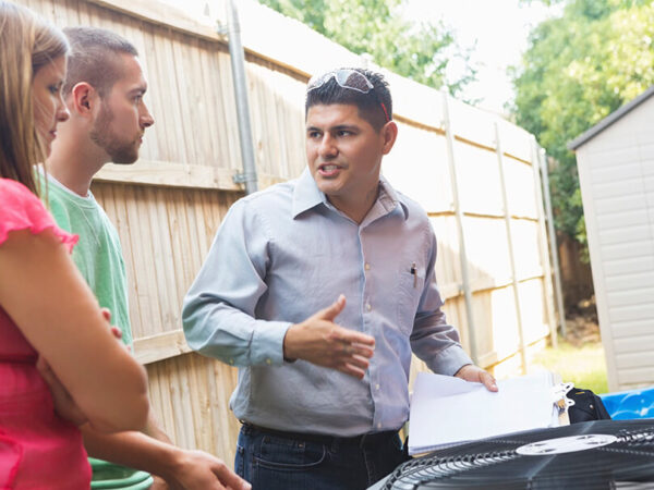 Male technician talking to a couple next to their air conditioner