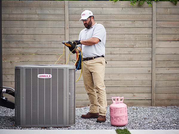 Air Conditioner technician standing next to AC ensuring proper function