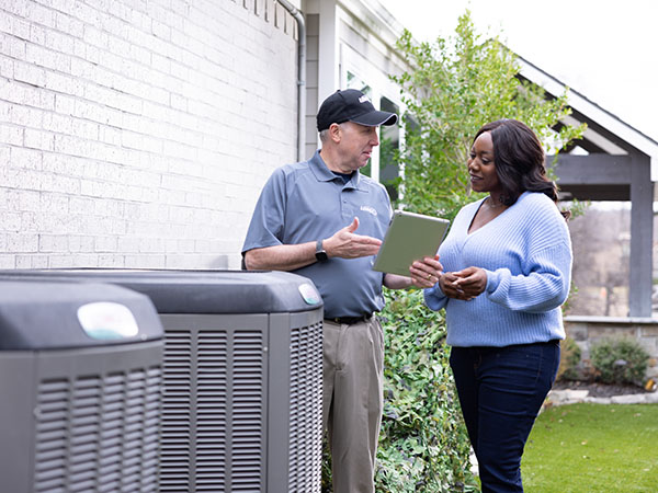 Air conditioner technician standing with customer explaining repair options
